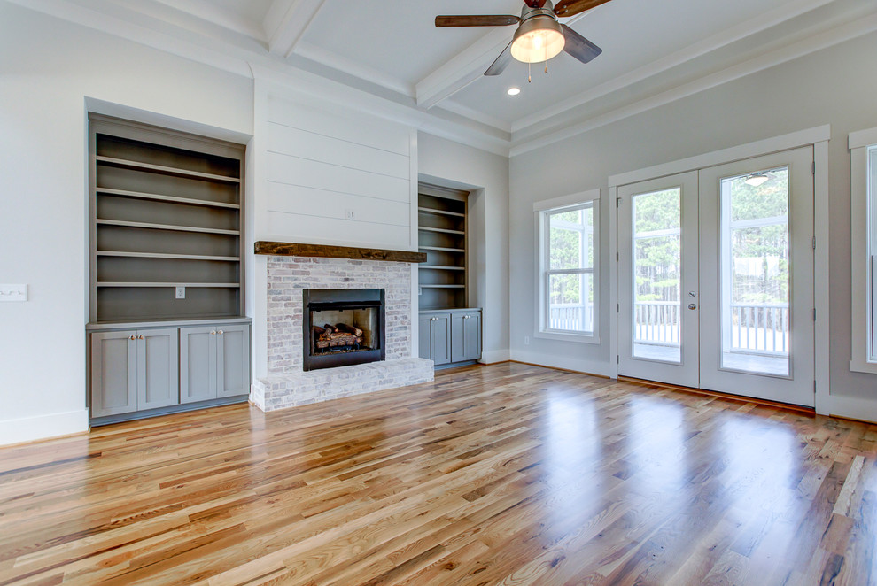 Medium sized country open plan living room in Raleigh with grey walls, light hardwood flooring, a standard fireplace, a brick fireplace surround and brown floors.