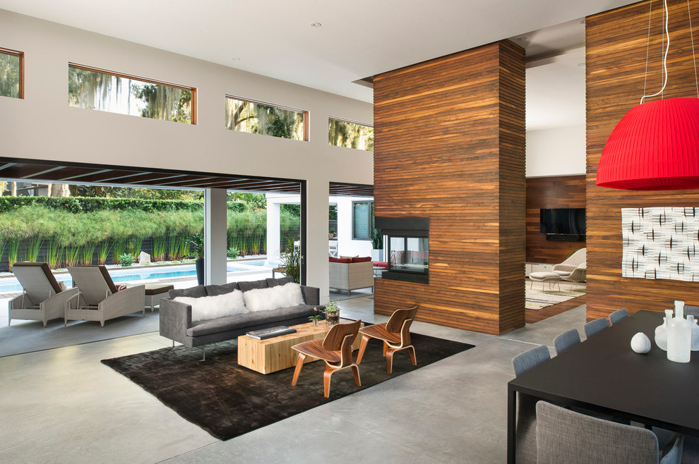 Пример оригинального дизайна: парадная, открытая гостиная комната в современном стиле с бетонным полом, двусторонним камином и ковром на полу