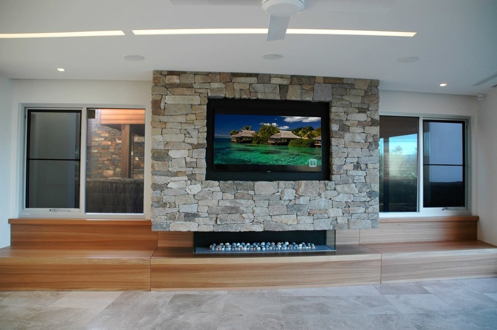 Contemporary open plan living room in Darwin with a stone fireplace surround and a built-in media unit.
