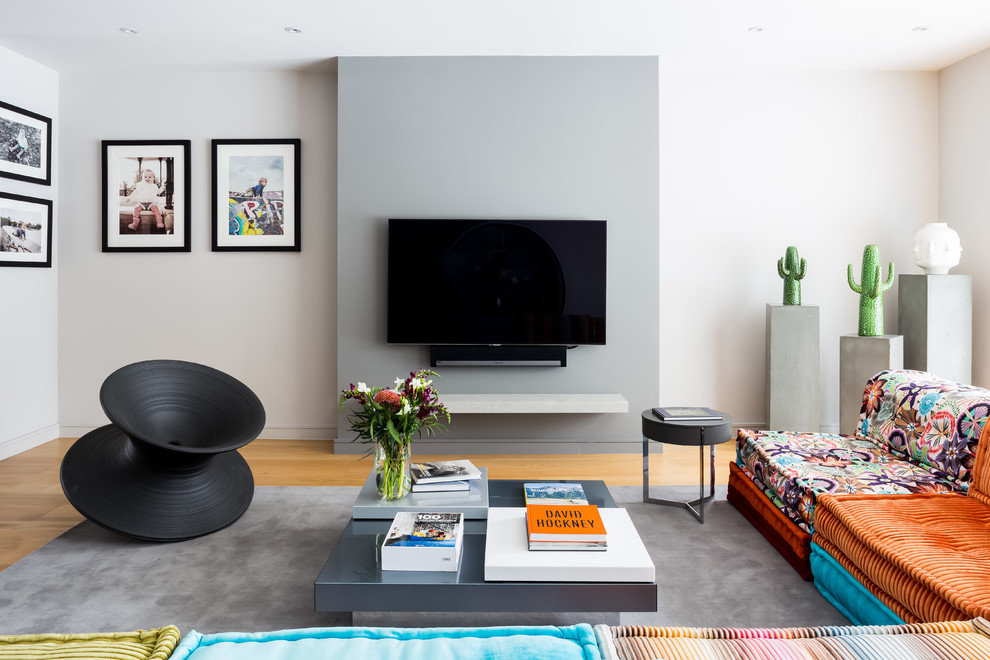 Cette image montre un salon design avec un mur gris, parquet clair, aucune cheminée, un téléviseur fixé au mur et un sol beige.