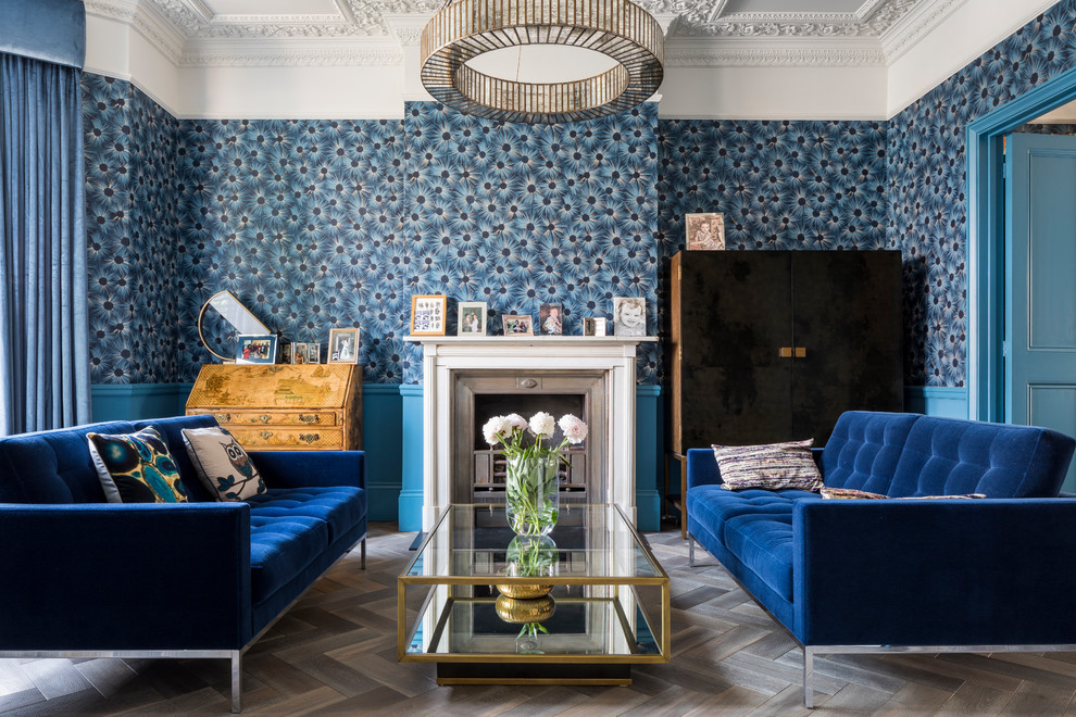 На фото: изолированная гостиная комната среднего размера в викторианском стиле с синими стенами, темным паркетным полом, стандартным камином, фасадом камина из камня и коричневым полом без телевизора