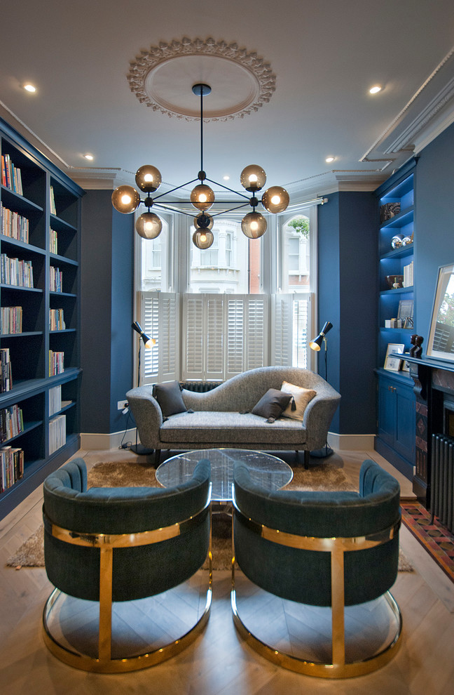 Ispirazione per un soggiorno design chiuso con pareti blu, parquet chiaro, camino classico, libreria, nessuna TV e pavimento beige