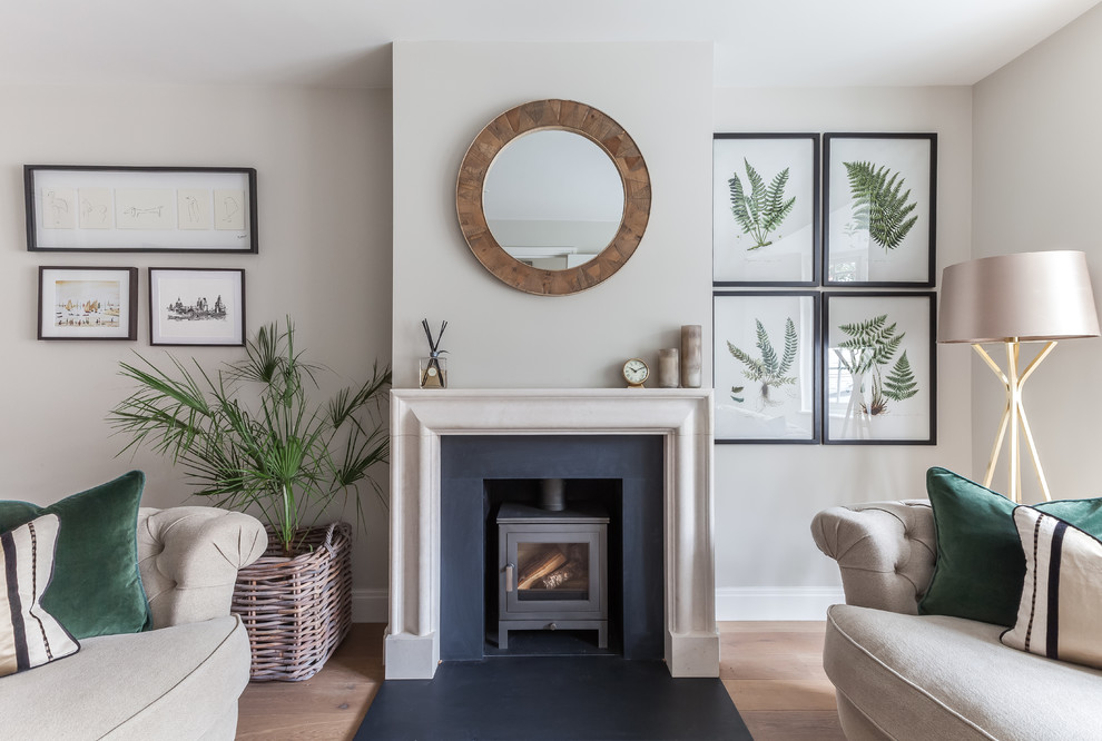 Living room - contemporary medium tone wood floor and brown floor living room idea in London with gray walls, a wood stove and a stone fireplace