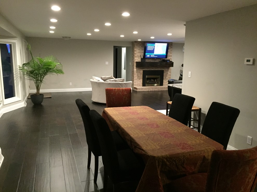 На фото: большая открытая гостиная комната в современном стиле с серыми стенами и темным паркетным полом без камина, телевизора с