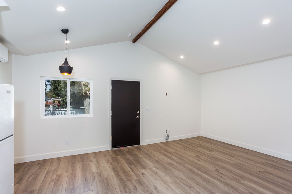 Cette photo montre un salon tendance de taille moyenne et ouvert avec une salle de réception, un mur blanc, un sol en vinyl, un téléviseur fixé au mur et un sol marron.