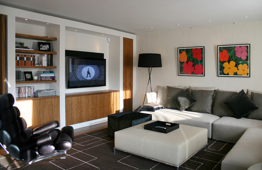 Modelo de salón para visitas abierto actual de tamaño medio con paredes blancas, suelo de madera en tonos medios y televisor colgado en la pared