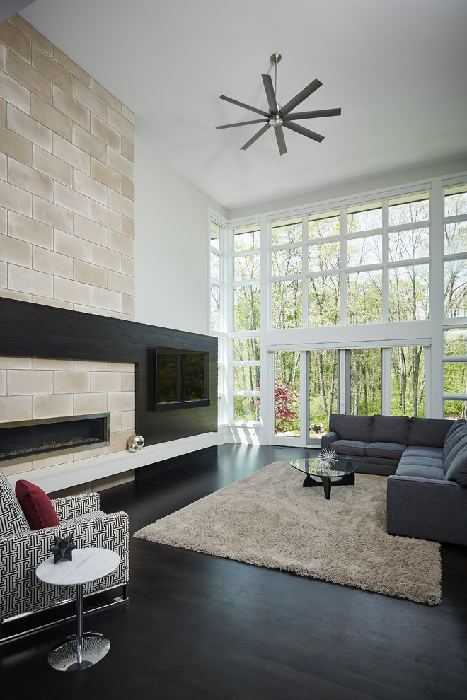 Modelo de salón moderno con paredes blancas, suelo de madera oscura, chimenea lineal, marco de chimenea de baldosas y/o azulejos, pared multimedia y suelo negro