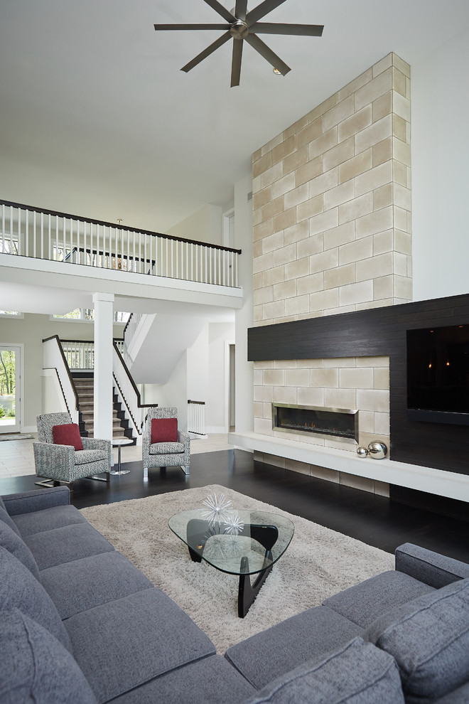 Cette photo montre un salon moderne ouvert avec un mur blanc, parquet foncé, une cheminée standard, un manteau de cheminée en carrelage, un téléviseur encastré, un sol noir et un plafond voûté.
