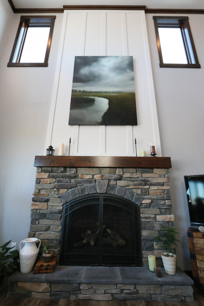 Exemple d'un salon nature de taille moyenne et ouvert avec un mur gris, une cheminée standard, un manteau de cheminée en pierre et un téléviseur indépendant.