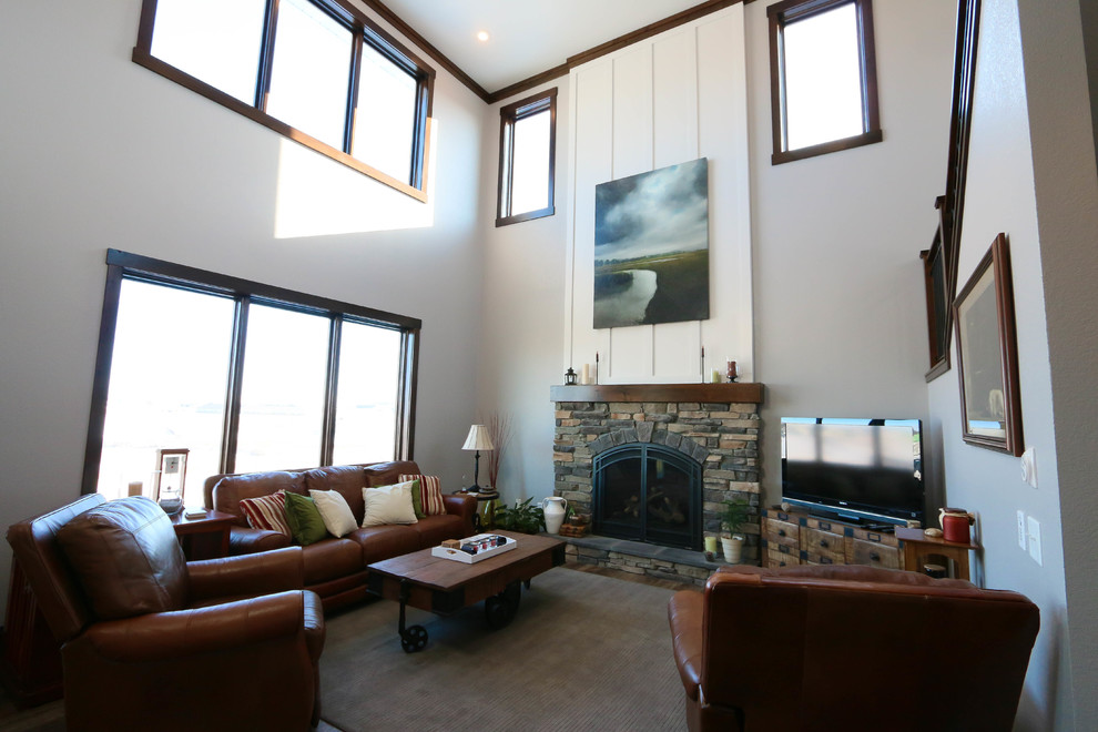 На фото: открытая гостиная комната среднего размера в стиле кантри с серыми стенами, стандартным камином, фасадом камина из камня и отдельно стоящим телевизором с