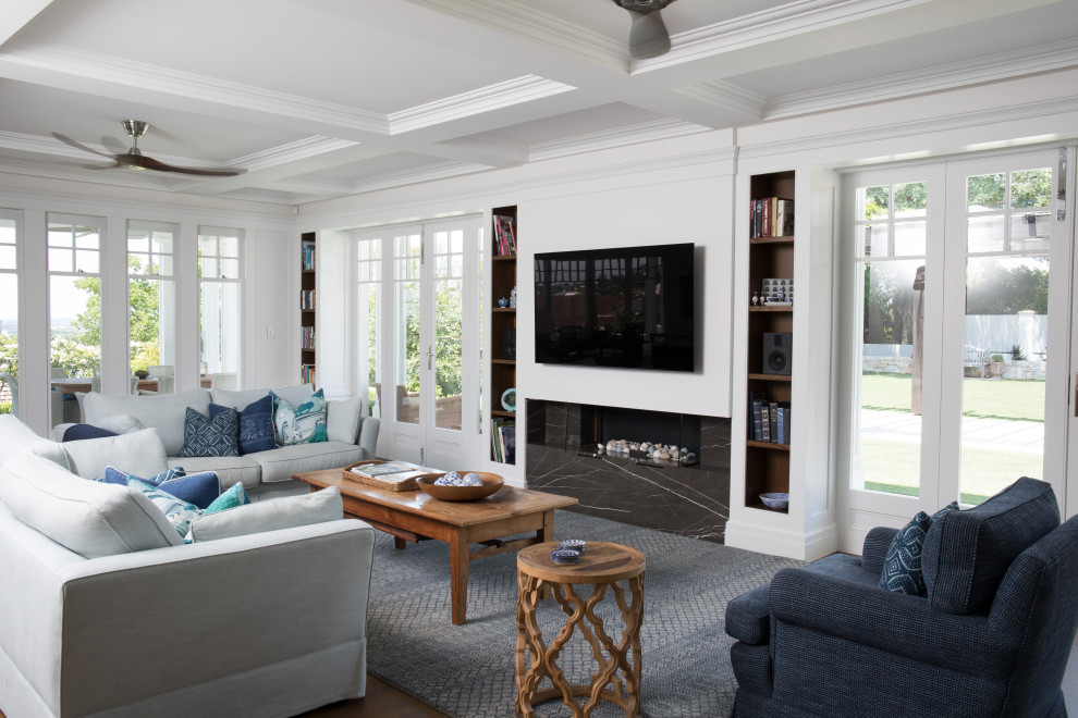 На фото: открытая гостиная комната в классическом стиле с фасадом камина из камня, телевизором на стене, кессонным потолком, белыми стенами, паркетным полом среднего тона, горизонтальным камином и коричневым полом