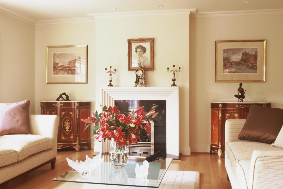Idée de décoration pour un grand salon tradition fermé avec un mur beige, un sol en bois brun, une cheminée standard, un manteau de cheminée en pierre et un sol beige.