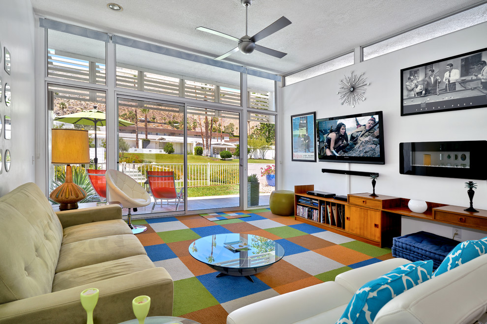 Foto på ett 50 tals vardagsrum, med vita väggar, heltäckningsmatta, en väggmonterad TV och flerfärgat golv