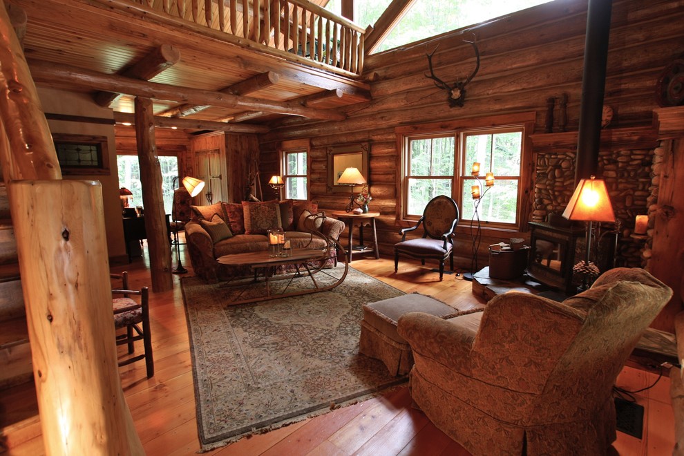 Diseño de salón abierto rural grande sin televisor con paredes marrones, suelo de madera en tonos medios y estufa de leña