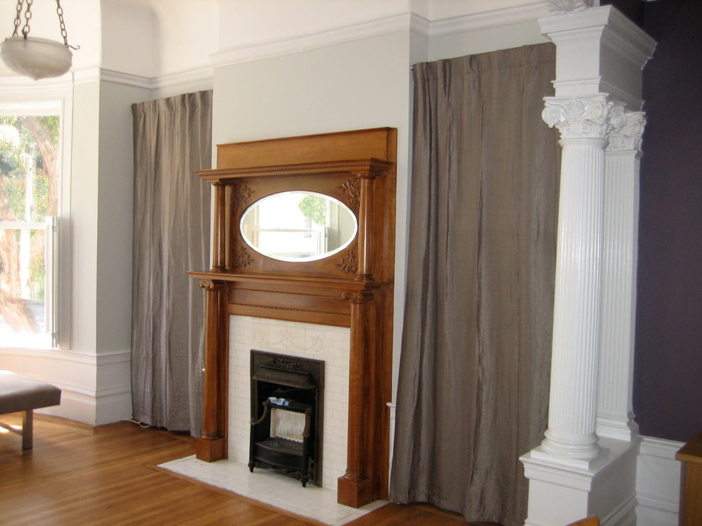 Imagen de salón cerrado tradicional pequeño con paredes grises, suelo de madera clara, todas las chimeneas, marco de chimenea de baldosas y/o azulejos y televisor colgado en la pared