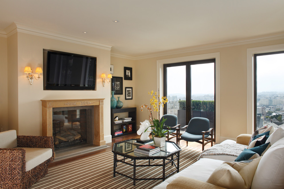 Immagine di un soggiorno tradizionale con pareti beige, camino classico e TV a parete
