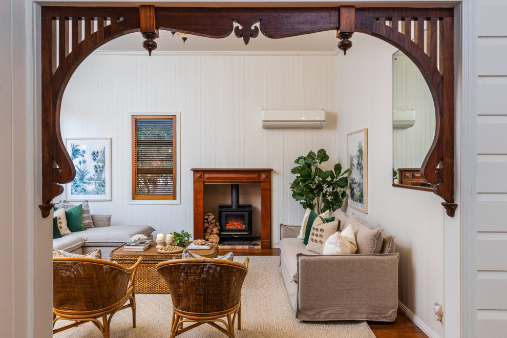 Abgetrenntes Klassisches Wohnzimmer mit weißer Wandfarbe, braunem Holzboden, Kaminofen, braunem Boden, Holzdielendecke und Holzdielenwänden in Brisbane