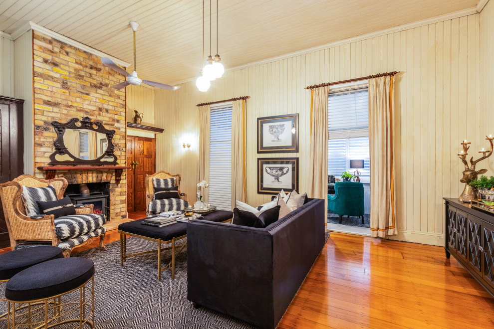 Klassisches Wohnzimmer mit beiger Wandfarbe, braunem Holzboden, Kaminofen, Kaminumrandung aus Backstein, braunem Boden, Holzdielendecke und Holzdielenwänden in Brisbane