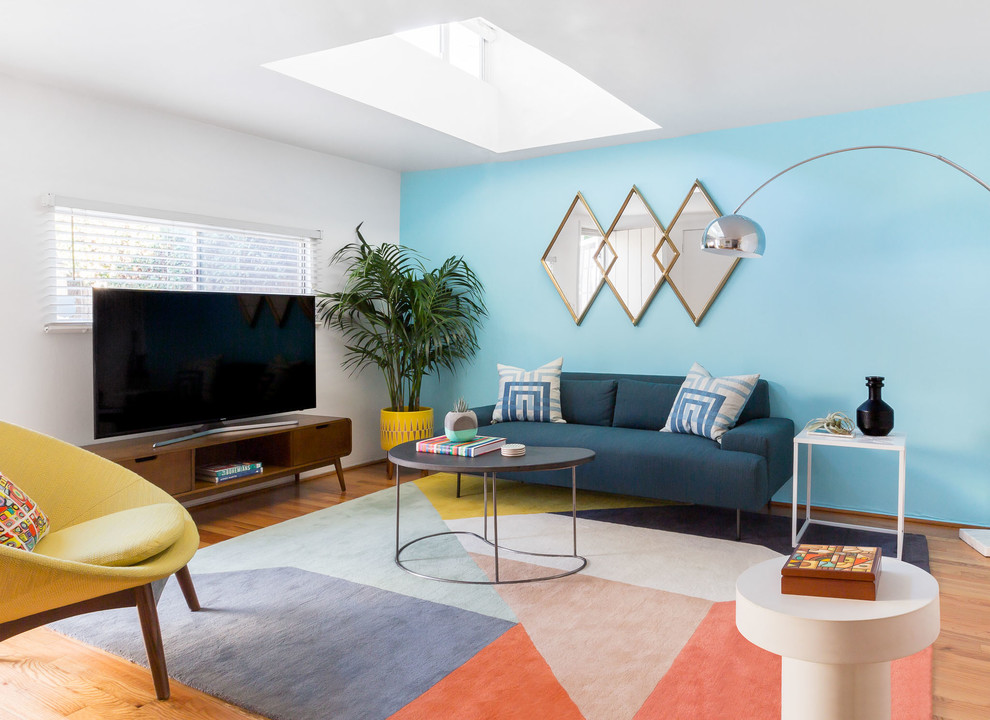 Bild på ett funkis vardagsrum, med blå väggar, mellanmörkt trägolv, en fristående TV och brunt golv