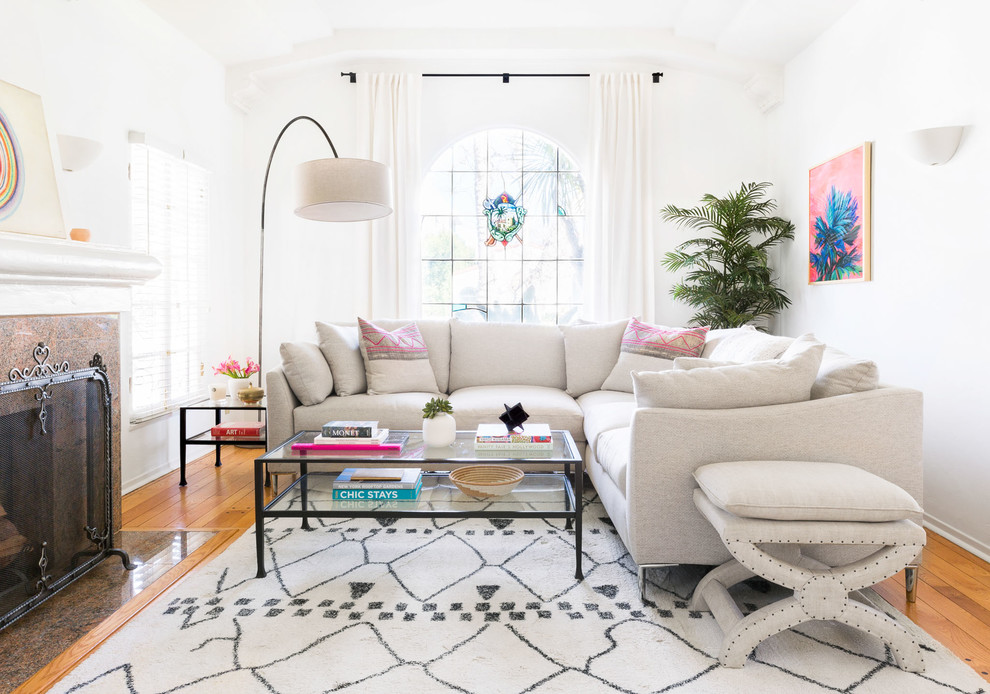 Klassisches Wohnzimmer mit weißer Wandfarbe, braunem Holzboden, Kamin, gefliester Kaminumrandung und braunem Boden in Los Angeles