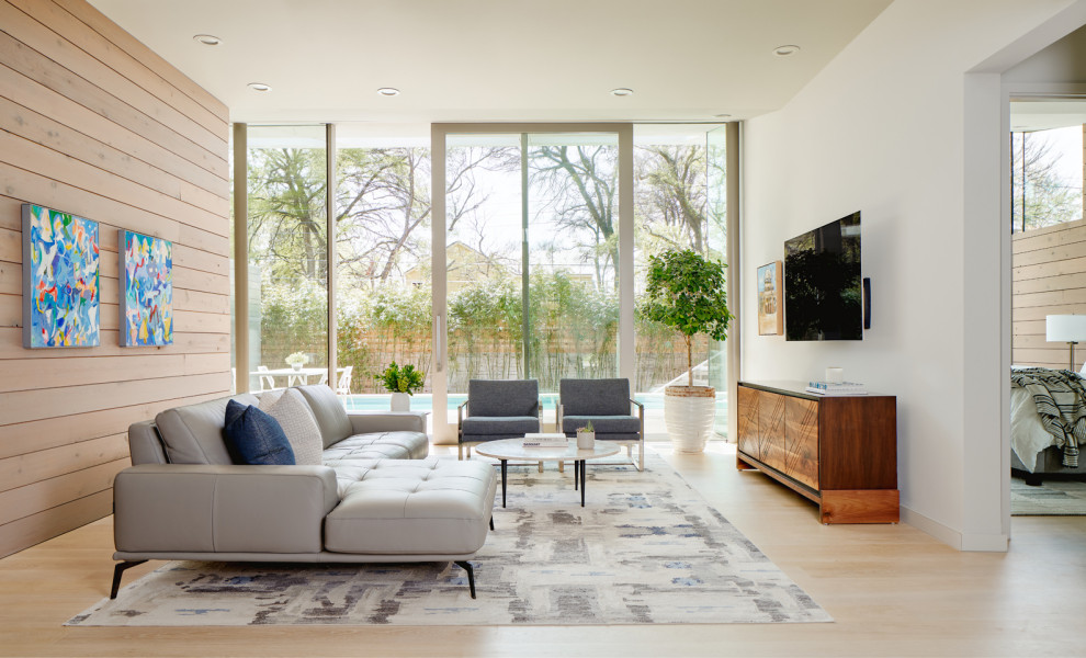Immagine di un soggiorno design di medie dimensioni e aperto con parquet chiaro e TV a parete