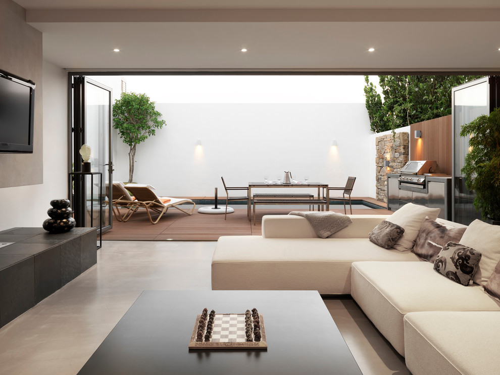 Свежая идея для дизайна: открытая гостиная комната в современном стиле с белыми стенами, бетонным полом, телевизором на стене и серым полом - отличное фото интерьера