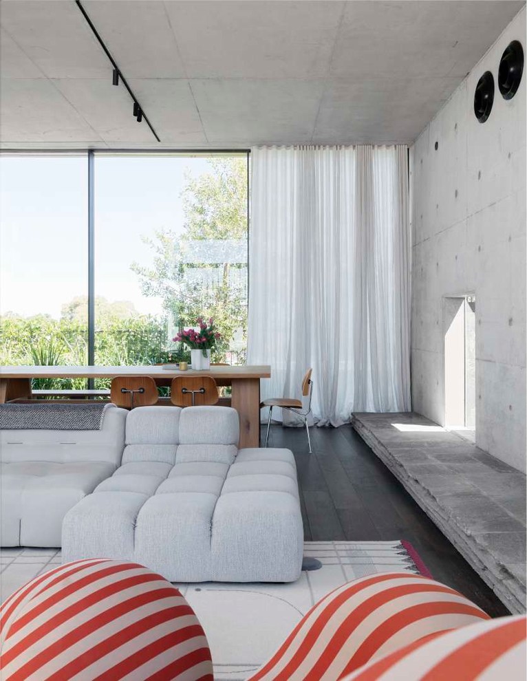 Foto de salón abierto minimalista con paredes grises, marco de chimenea de piedra y suelo gris