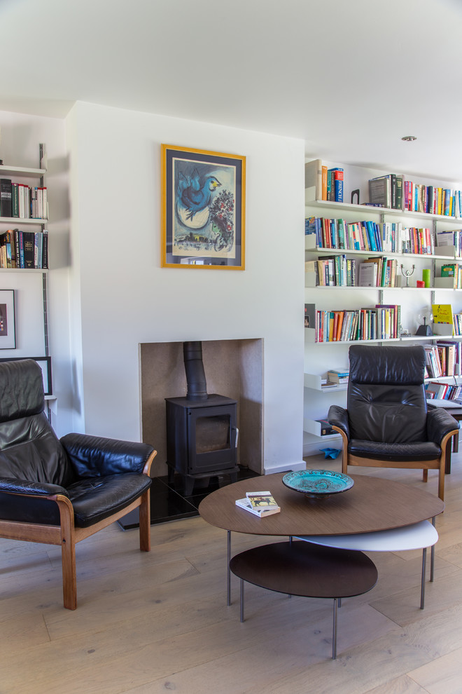 Idee per un soggiorno contemporaneo con libreria, pareti bianche, parquet chiaro, stufa a legna e pavimento beige