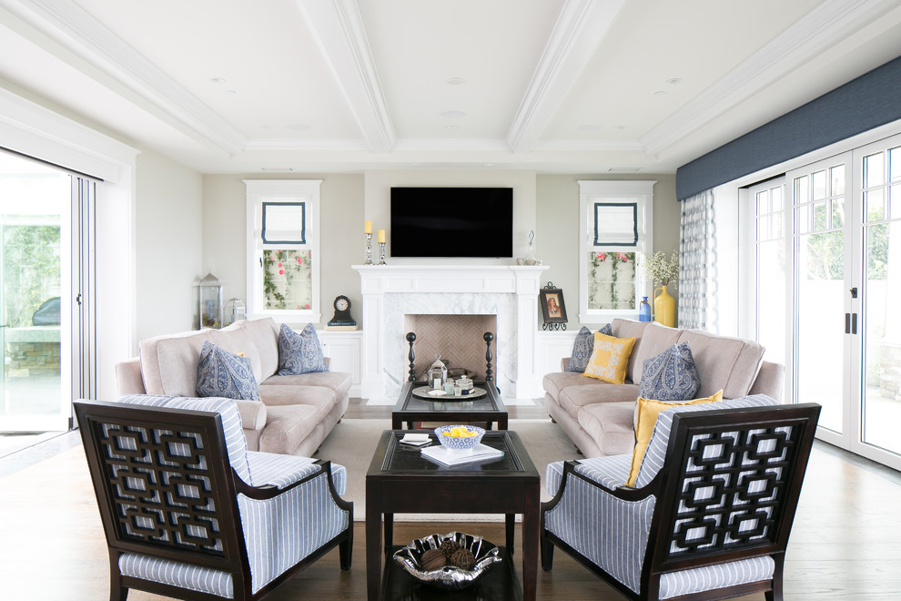 Repräsentatives Klassisches Wohnzimmer mit blauer Wandfarbe, hellem Holzboden, Kamin, Kaminumrandung aus Stein und TV-Wand in Orange County