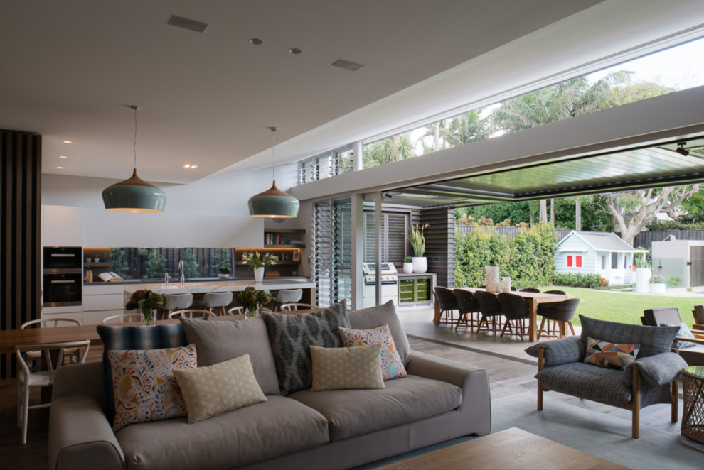 Inspiration pour un grand salon design ouvert avec un mur beige, un sol en bois brun, un téléviseur encastré et un sol marron.