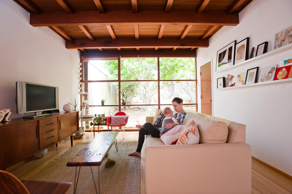 Exempel på ett modernt vardagsrum, med vita väggar och en fristående TV