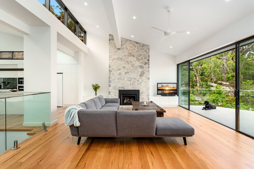 Großes, Repräsentatives, Offenes Modernes Wohnzimmer mit weißer Wandfarbe, braunem Holzboden, Kamin, freistehendem TV und braunem Boden in Sydney