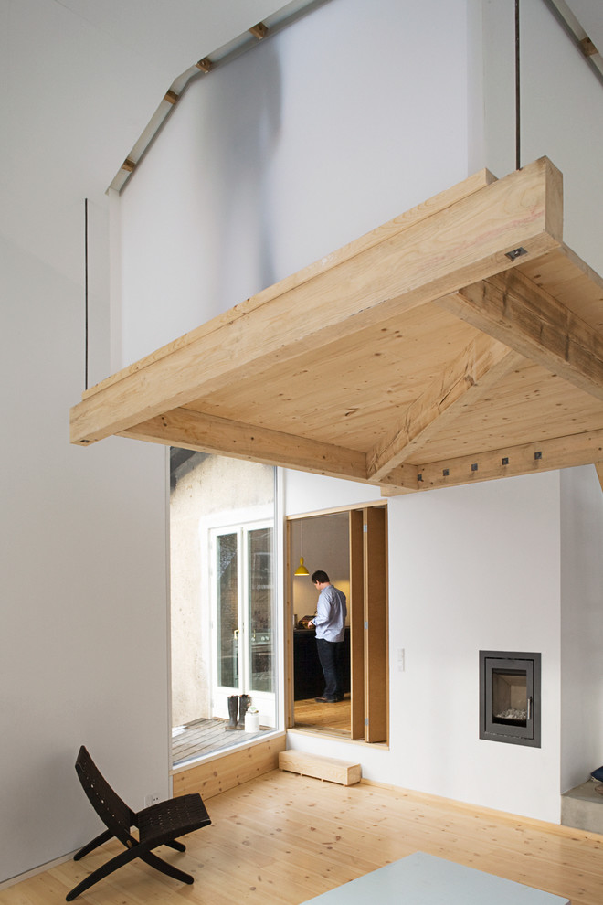 Modelo de salón tipo loft escandinavo pequeño con paredes blancas, suelo de madera en tonos medios y todas las chimeneas