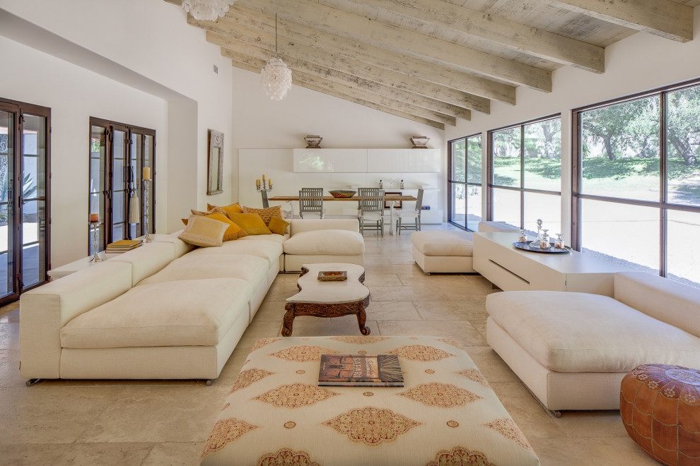 Großes, Offenes Mediterranes Wohnzimmer mit Kalkstein, beigem Boden, freigelegten Dachbalken und weißer Wandfarbe in Santa Barbara