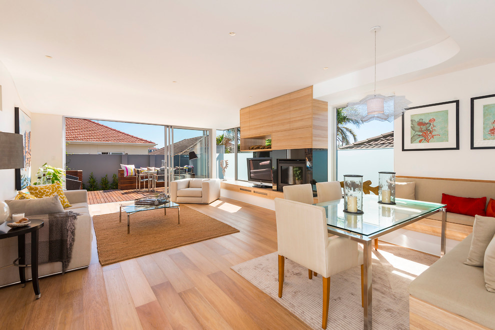 Großes, Offenes Modernes Wohnzimmer mit weißer Wandfarbe, Kamin, freistehendem TV und hellem Holzboden in Sonstige