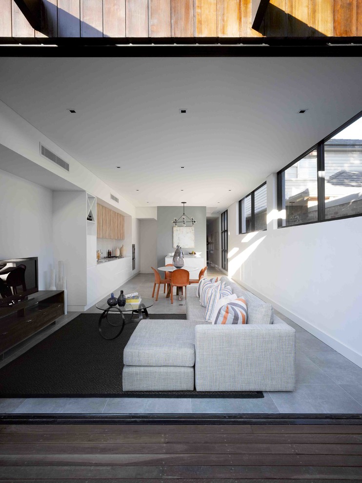 Mittelgroßes, Offenes Modernes Wohnzimmer mit weißer Wandfarbe, Kalkstein, freistehendem TV und grauem Boden in Sydney