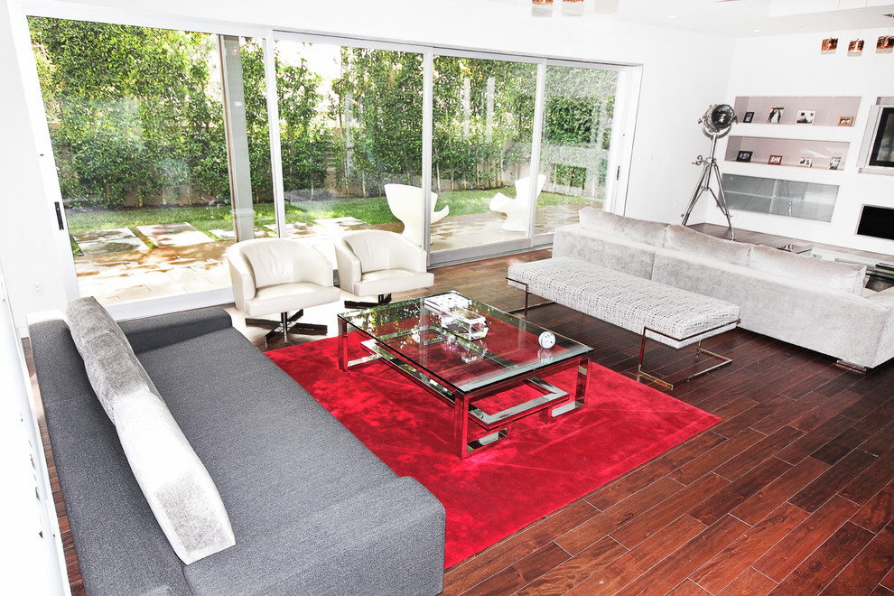 Immagine di un grande soggiorno design aperto con pavimento in legno massello medio e TV a parete
