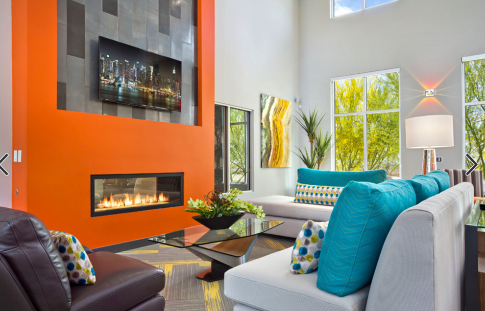 フェニックスにある高級な中くらいなモダンスタイルのおしゃれなLDK (オレンジの壁、カーペット敷き、両方向型暖炉、漆喰の暖炉まわり、壁掛け型テレビ、グレーの床) の写真