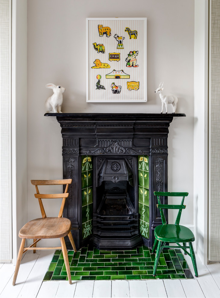 Nordisches Wohnzimmer mit grauer Wandfarbe, gebeiztem Holzboden, Kamin, gefliester Kaminumrandung und weißem Boden in London