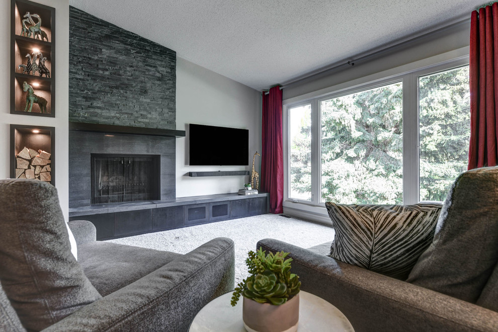 Стильный дизайн: маленькая открытая гостиная комната в современном стиле с серыми стенами, ковровым покрытием, стандартным камином, фасадом камина из плитки, телевизором на стене и серым полом для на участке и в саду - последний тренд
