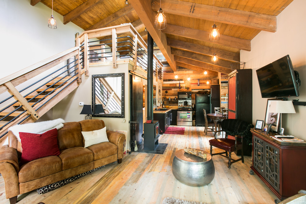 Esempio di un piccolo soggiorno stile rurale stile loft con pareti beige, pavimento in legno massello medio, stufa a legna, cornice del camino in metallo e TV a parete