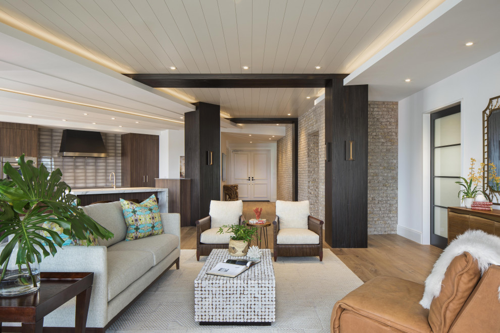 Exemple d'un grand salon tendance ouvert avec une salle de réception, un mur blanc, un sol en bois brun, aucun téléviseur, un sol marron et un mur en parement de brique.