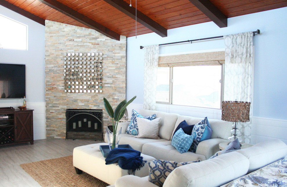 Идея дизайна: двухуровневая гостиная комната среднего размера в морском стиле с синими стенами, полом из керамогранита, угловым камином, фасадом камина из камня и телевизором на стене