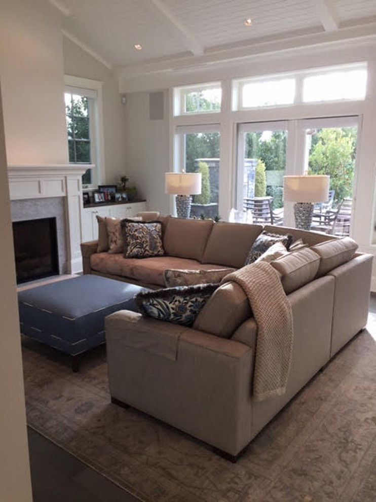 Offenes Maritimes Wohnzimmer mit beiger Wandfarbe, Kamin, Kaminumrandung aus Stein, TV-Wand und braunem Boden in Vancouver