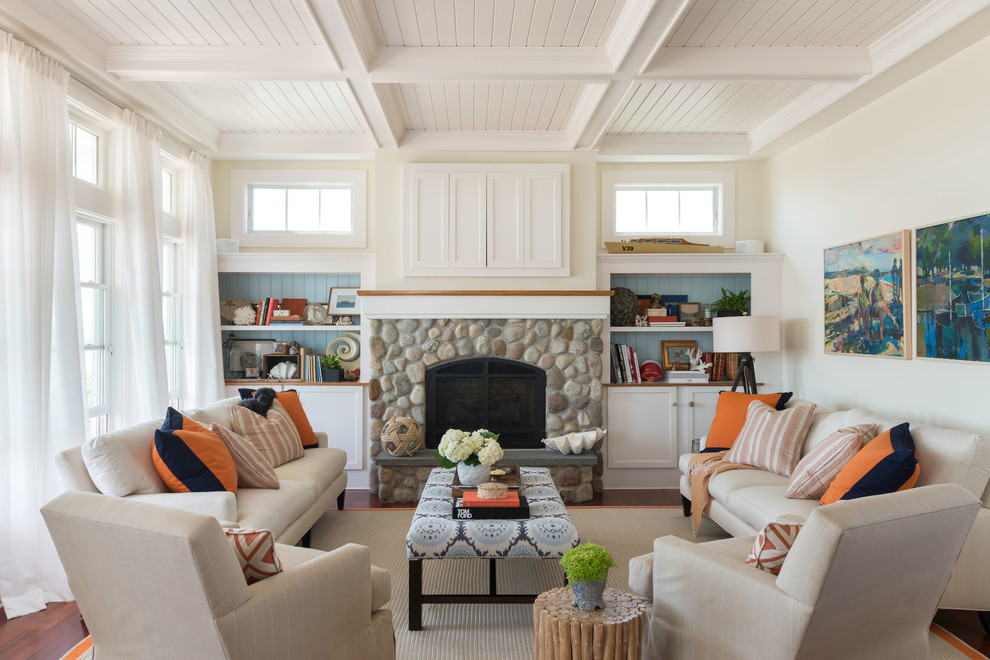 Inspiration for a mid-sized coastal medium tone wood floor living room library remodel in Providence with beige walls, a standard fireplace, a stone fireplace and a concealed tv