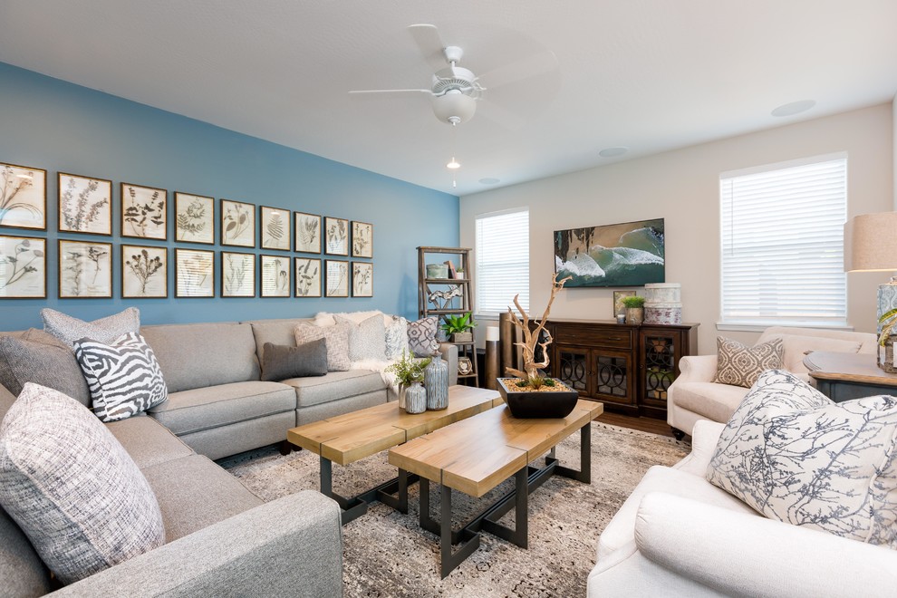 Modelo de salón abierto costero de tamaño medio sin chimenea con paredes azules, suelo de madera en tonos medios, televisor colgado en la pared y suelo marrón