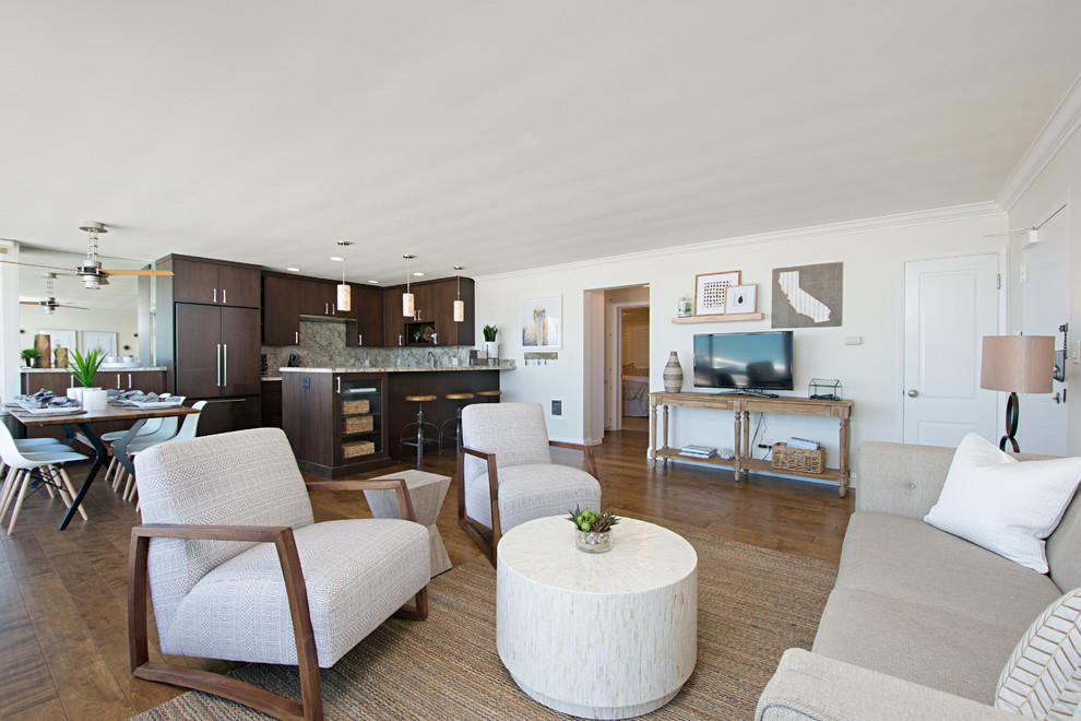 Cette image montre un grand salon marin ouvert avec un mur blanc, parquet foncé, un téléviseur indépendant et un sol marron.
