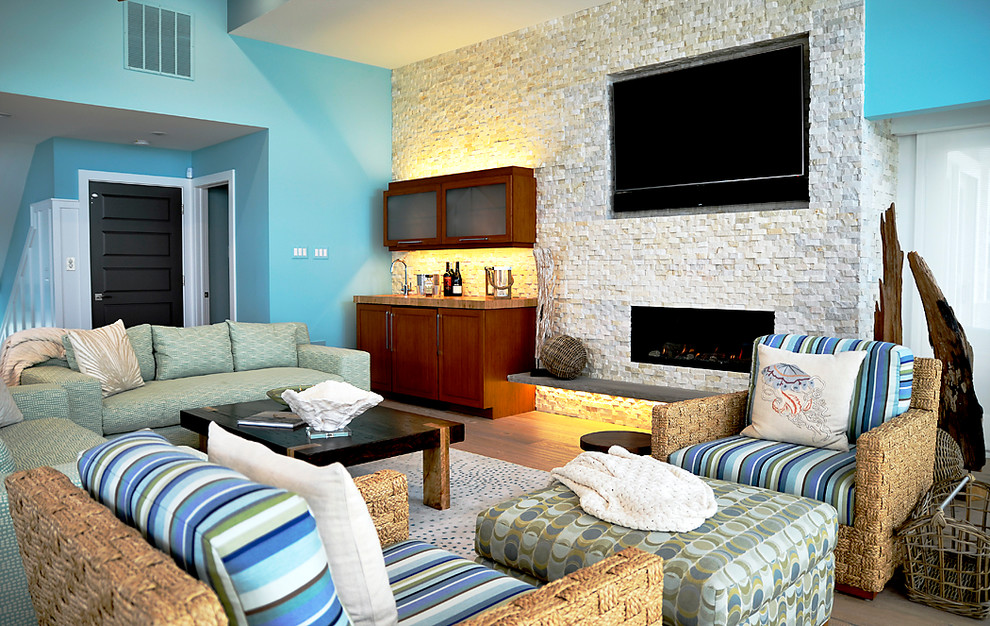 Ejemplo de salón abierto marinero extra grande con paredes azules, suelo de madera clara, todas las chimeneas, marco de chimenea de piedra y televisor colgado en la pared