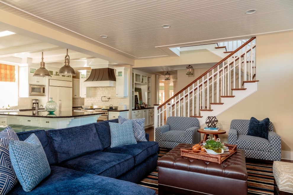 Стильный дизайн: открытая гостиная комната в морском стиле с бежевыми стенами и синим диваном - последний тренд