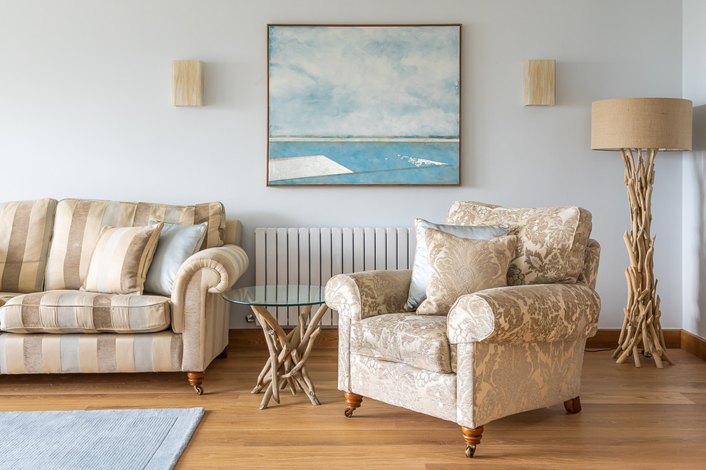 Design ideas for a coastal living room in Essex with a reading nook, blue walls, light hardwood flooring and a freestanding tv.